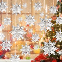 snowflakes hanging from strings in front of a christmas tree