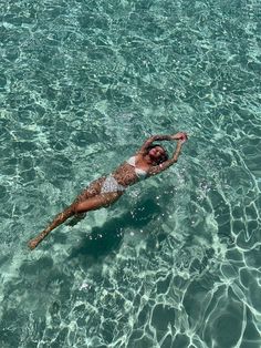 a man floating in the ocean on top of a body of water with no shirt