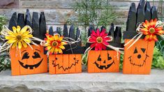 three bags decorated with pumpkin faces and flowers are sitting in front of a black fence