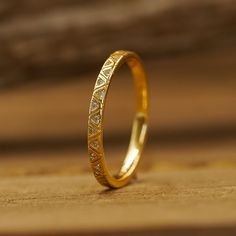 a gold wedding band with small diamonds on the inside, sitting on a wooden surface