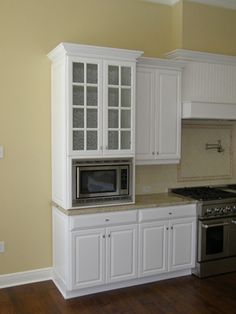 an empty kitchen with white cabinets and stainless steel stove top oven in the middle of the room