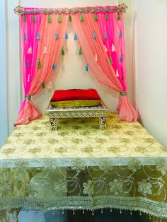 a bed with pink drapes on top of it next to a red pillow and curtain