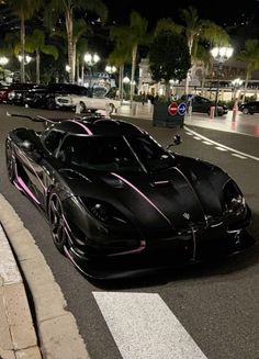 a black sports car parked on the side of a road at night with palm trees in the background