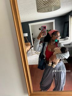 a woman is taking a selfie in the mirror with her baby and looking at herself