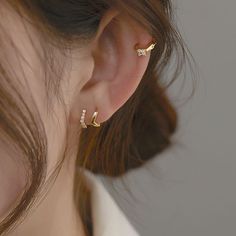 a close up of a person's ear with two small diamond earrings on it