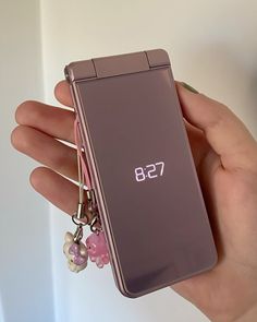 a hand holding a purple cell phone with a keychain attached to the back