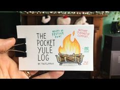 the pocket yule log is being held up by someone's hand in front of a fireplace