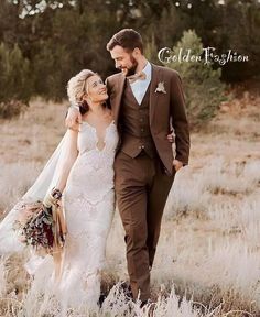 a bride and groom are walking through the field together in their wedding attire, holding each other's hand