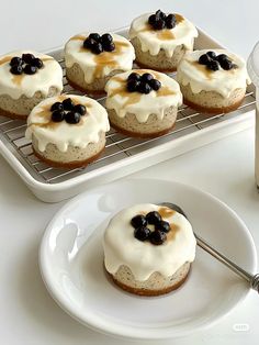 there are six cookies with blueberries on the top and one has cream frosting