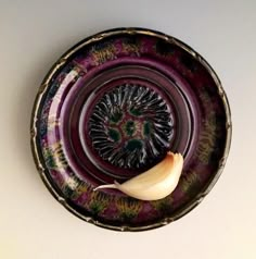 an onion sitting on top of a purple and green plate with a flower in the center