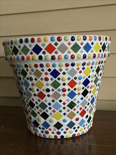 a colorful basket sitting on top of a wooden table next to a wall and window