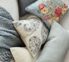 pillows and blankets are arranged on a couch with blue throw pillows, gray throw pillow covers, and white throw pillows