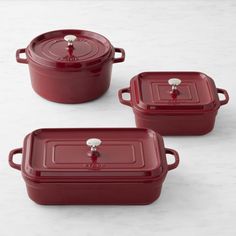 three red casserole dishes sitting on top of a white countertop next to each other