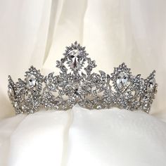 Our sophisticated bridal tiara features intricate detailing guaranteed to make an unforgettable statement on your big wedding day. With dazzling crystals and a refined elaborate motif, this glowing crystal tiara will complement a multitude of bridal hair styles on your special day. -Genuine crystals -Approximately 2.5in at the highest point x 11in across (6.4cm x 27.9cm) -Rhodium plated non-tarnish finish for brilliance Shown with earrings E168 Wedding Teardrop Crown Headpiece, Regal Structured Crown Wedding Headpiece, Regal Structured Crown Headpiece For Wedding, Regal Wedding Headpiece With Structured Crown, Regal Tall Crown Headpieces For Wedding, Regal Tall Crown For Wedding, Elegant Crystal Crown For Party, Elegant Crystal Crown For Wedding, Teardrop Crown Headpiece With Rhinestones For Wedding