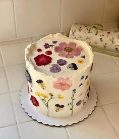 a decorated cake sitting on top of a white counter next to a plate with flowers