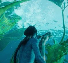 a person standing in front of some plants and looking at the water with an underwater view