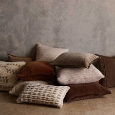 a pile of pillows sitting on top of a floor next to a wall with a vase