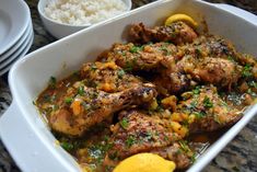 a white dish filled with meat and vegetables next to rice on a counter top,