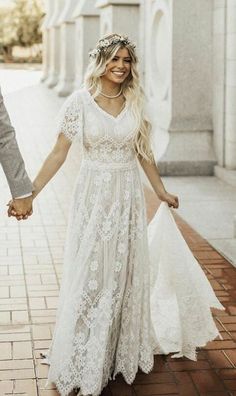 a bride and groom holding hands while walking down the street in their wedding gowns