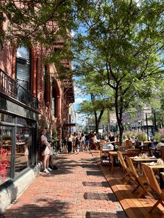 people are sitting at tables outside on the sidewalk