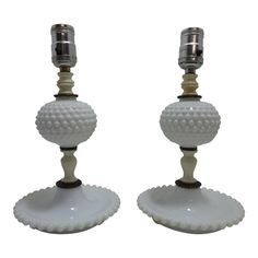 two white glass candlesticks sitting on top of each other