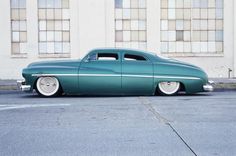 an old green car parked in front of a building