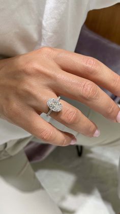 a woman's hand with a diamond ring on her left hand and a white shirt