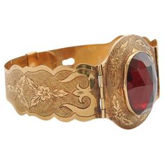 This antique bracelet is a stunning example of fine craftsmanship from a bygone era, likely dating from the late 19th to early 20th century. The bracelet is crafted from 14 karat gold, known for its durability and warm, rich color, which has developed a subtle patina over time. The centerpiece of the bracelet is a large, oval-shaped garnet, expertly cut in the rose-cut style. This cut, characterized by its flat base and domed, faceted top, is designed to maximize the stone's brilliance and depth of color. The garnet is a deep, rich red with flashes of lighter hues that catch the light beautifully, adding a touch of vibrant color to the piece. Garnets were popular gemstones in antique jewelry, often associated with love, passion, and protection. The bracelet features two hinged sections tha Engraved Bangle Bracelet, Engraved Bangle, Almandine Garnet, Yellow Gold Bangle, Antique Bracelets, Victorian Gold, Gold Engraving, Bygone Era, Engraved Bracelet