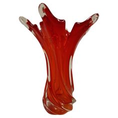 a red glass vase sitting on top of a white table