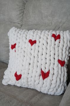 a crocheted pillow with red hearts on it