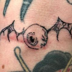 a close up of a person's arm with a bat tattoo design on it