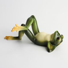 a green frog figurine laying on its back with it's legs spread out