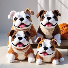 three stuffed dogs sitting next to each other on a bench with balls of yarn in the background