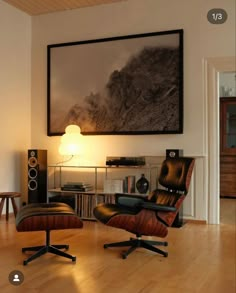 an empty living room with two chairs and a large painting on the wall above it