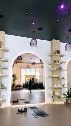 a person is standing in the middle of a room with shelves and candles on the wall