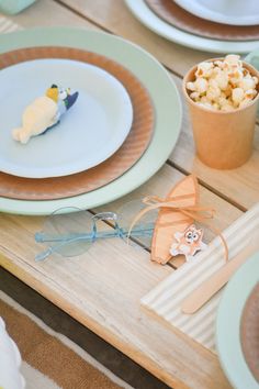 the table is set with plates, cups and glasses for children's birthday party