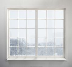 an open window in a white room with snow on the ground and trees behind it