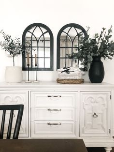 two black and white vases sitting on top of a dresser next to a mirror