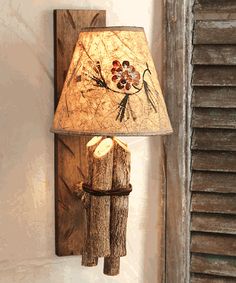 a lamp that is sitting on a wall next to a wooden pole with flowers painted on it