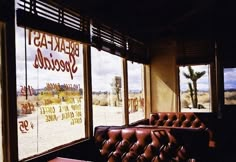 an empty restaurant with leather couches in front of large windows that read breakfast specials