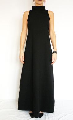 "This sleeveless black A-lined elegant maxi dress with a high collar (turtleneck collar) is minimalist, unique and trendy. It is cut under the chest, fitted on top and loose under the bust, so it looks great on all types of figures. Very elegant and flattering fitting. Details: Care: turn the garment inside out for better washing results, machine wash cold, tumble dry low, warm iron if needed Fabric: A medium/ heavier weight viscose jersey lycra blend Size: You may choose one of 7 standard sizes Minimalist Sleeveless Dresses For Workwear, Minimalist Sleeveless Dress For Work, Plain Fitted Sleeveless Maxi Dress, Sleeveless Fitted Plain Maxi Dress, Modern Black Maxi Dress For Work, Black Turtleneck Spring Dress, Black Minimalist Spring Dress, Stretch A-line Maxi Dress, Black Fitted Minimalist Dress