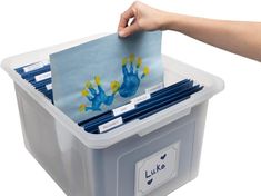 a person holding a blue handprinted card in a plastic container with dividers