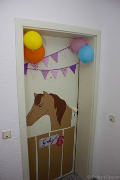 a door decorated with balloons and an image of a horse in a pen on it