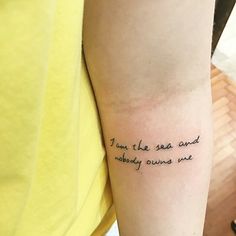 a person with a tattoo on their arm saying i am the sea and nobody owns me