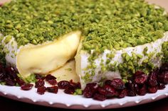 a cake covered in green and red cranberries on top of a white plate