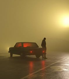 a person standing next to a car in the fog