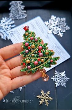 a hand holding a christmas tree brooch