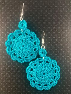 two crocheted earrings are shown on a black surface