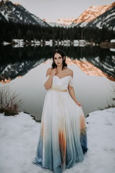 a woman standing in the snow wearing a dress with an ombrella on it