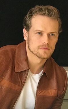 a man wearing a brown leather jacket and white t - shirt